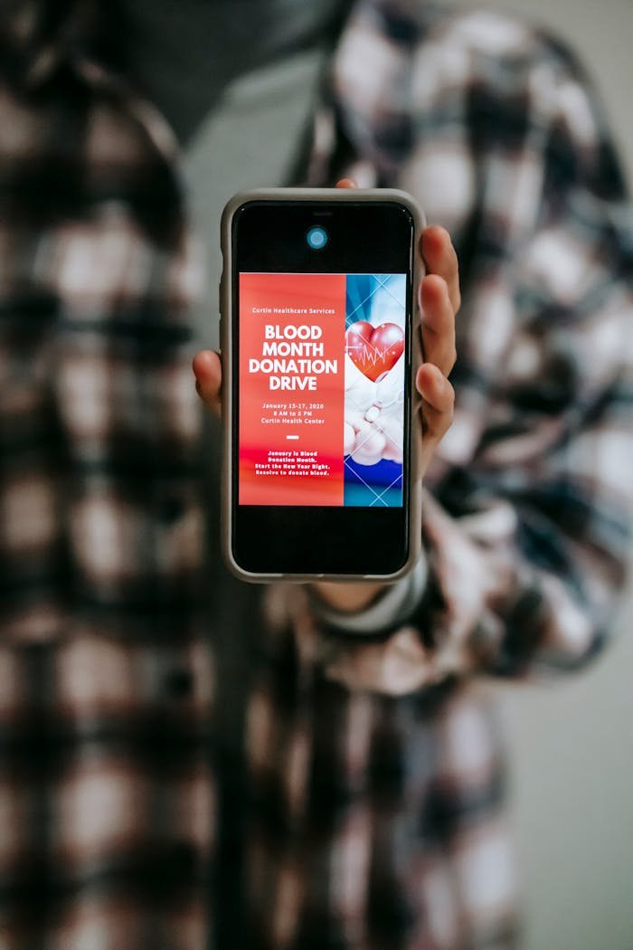 A smartphone displaying a blood donation drive advertisement held by a person.